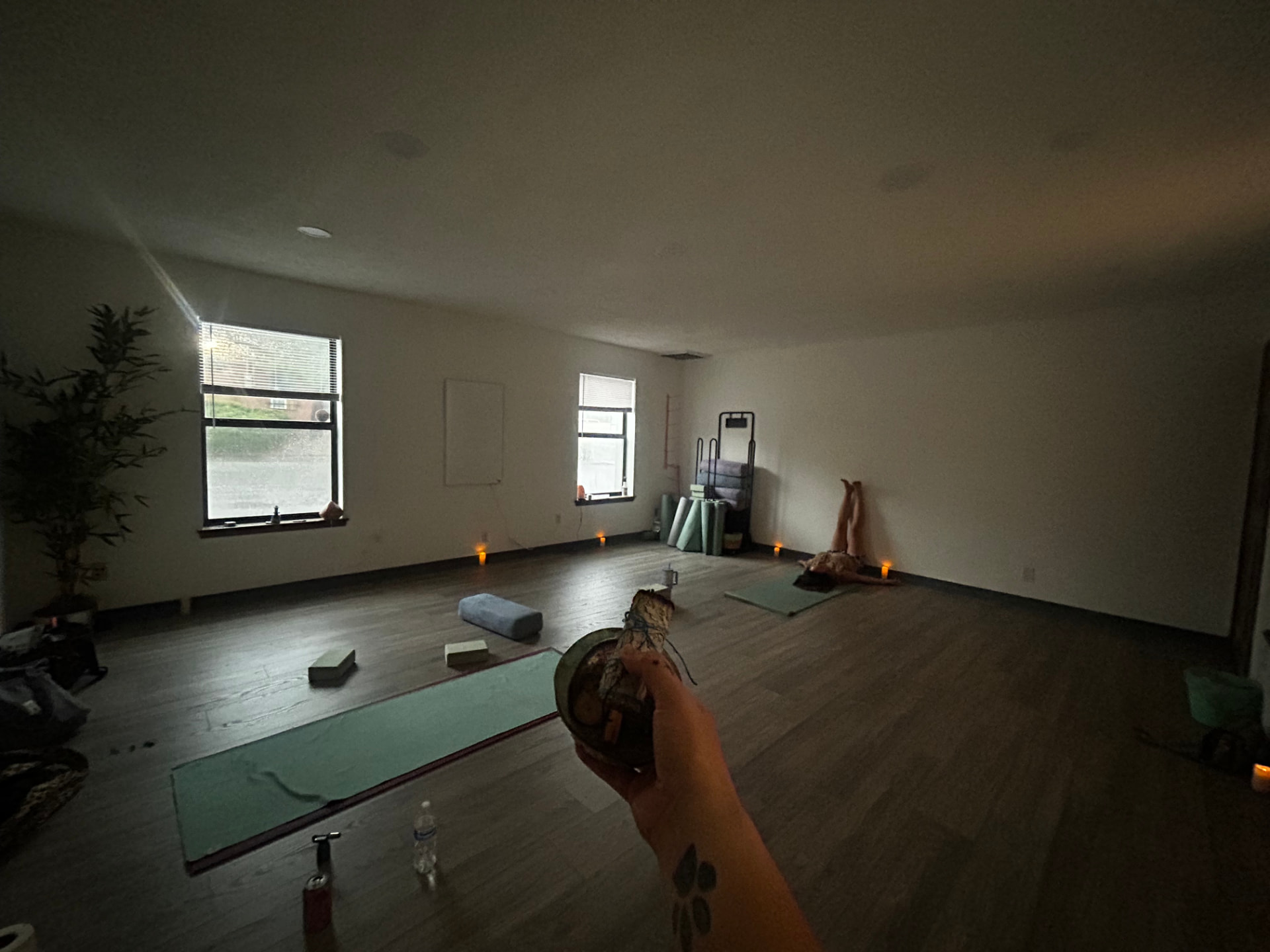 Candlelit studio at Shes Highest Healing with mats laid out, singing bowl, and warm window light